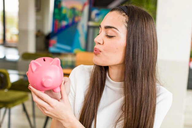 Hübsche junge Frau mit einem Sparschwein Sparkonzept Haus Innenarchitektur