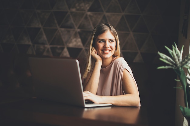 Hübsche junge Frau mit Laptop im Café