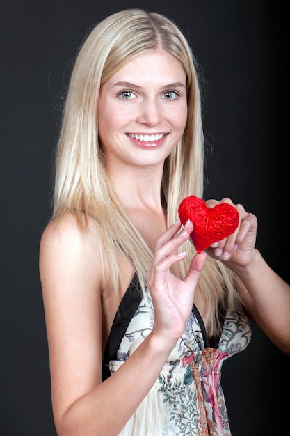 Hübsche junge Frau mit rotem Herzen auf schwarzem Hintergrund