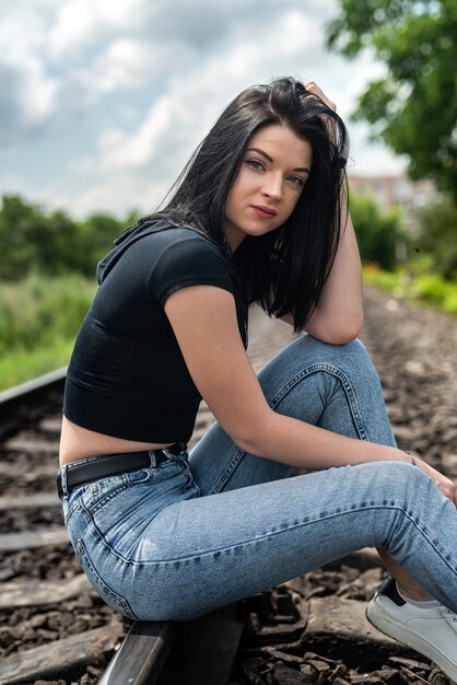 Hübsche junge Frau steht nahe den Bahngleisen, Sommerlebensstil