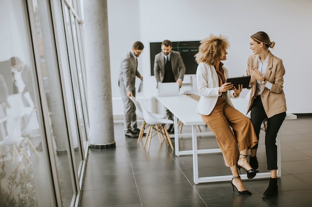 Hübsche junge Frauen mit digitalem Tablet im modernen Büro vor ihrem Team