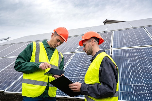 Hübsche junge, gesunde Arbeiter, die an der Installation von Solarmodulen arbeiten