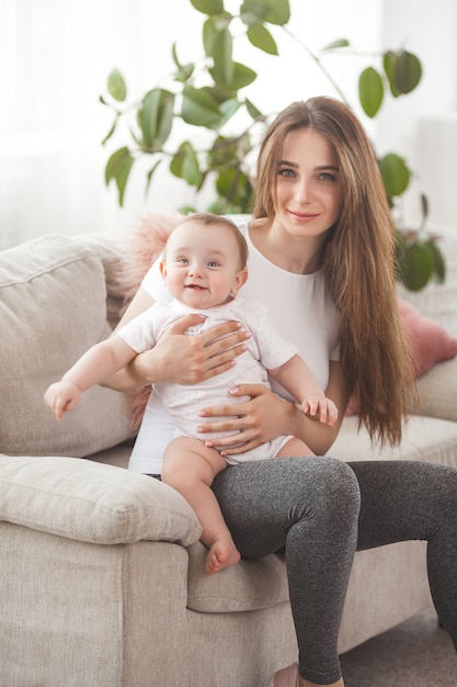 Hübsche junge Mutter, die ihr kleines Mädchen hält