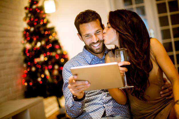 Hübsche junge Paare mit Tablette an Sylvesterabend