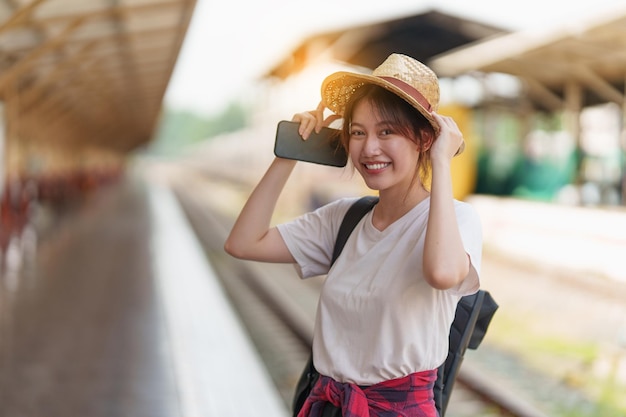 Hübsche junge Reisende Frau begeistert und plant Reise am Bahnhof Sommer- und Reise-Lifestyle-Konzept