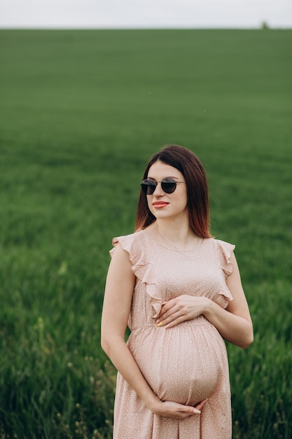 Hübsche junge schwangere Frau, die draußen in der Natur am Sommertag entspannt