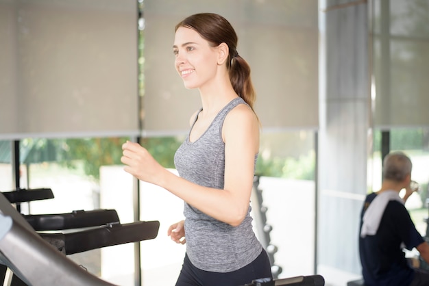 Hübsche junge Sportfrau läuft auf Laufband im Fitnessstudio