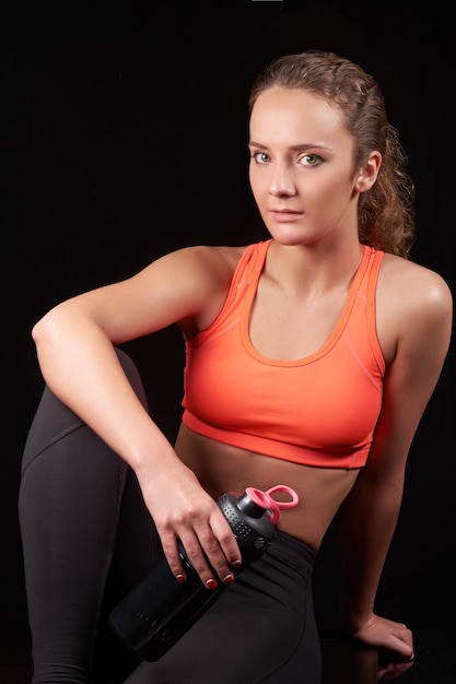 Hübsche kaukasische Fitnessfrau auf schwarzem lokalisiertem Hintergrund im Studio