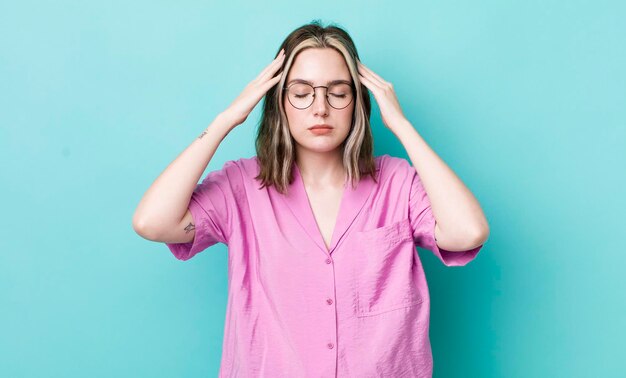 Hübsche kaukasische Frau, die konzentriert nachdenklich und inspiriert beim Brainstorming und Vorstellen mit den Händen auf der Stirn aussieht