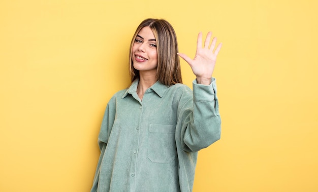 Hübsche kaukasische Frau, die lächelt und freundlich aussieht, Nummer fünf oder fünf mit der Hand nach vorne zeigt und herunterzählt