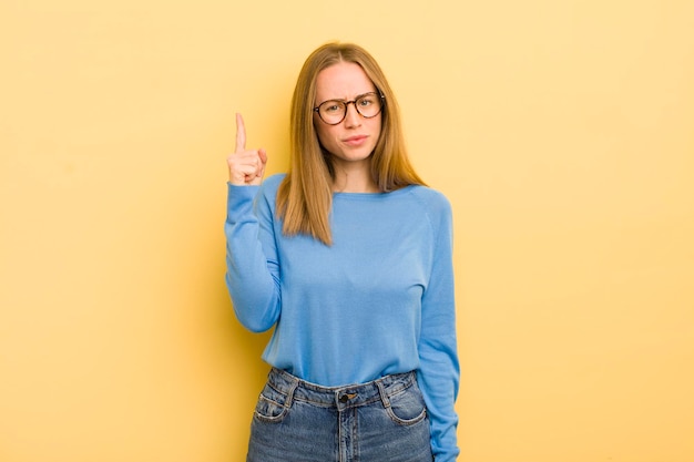 Hübsche kaukasische Frau, die sich wie ein Genie fühlt, das den Finger stolz in die Luft hält, nachdem sie eine großartige Idee verwirklicht hat, die Eureka sagt