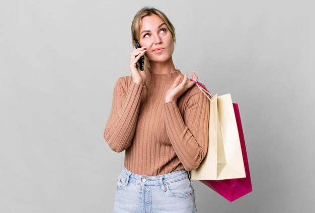 Hübsche kaukasische Frau mit Einkaufstüten und einem Smartphone