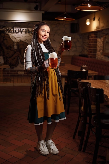Hübsche Kellnerin mit zwei Krügen Bier in der Hand in eine Bierkneipe