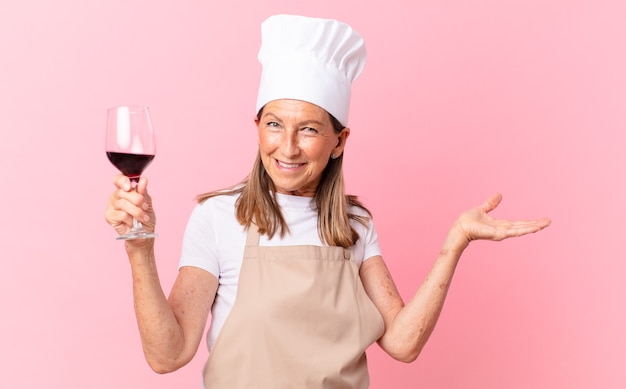 Hübsche Köchin mittleren Alters mit einem Glas Wein