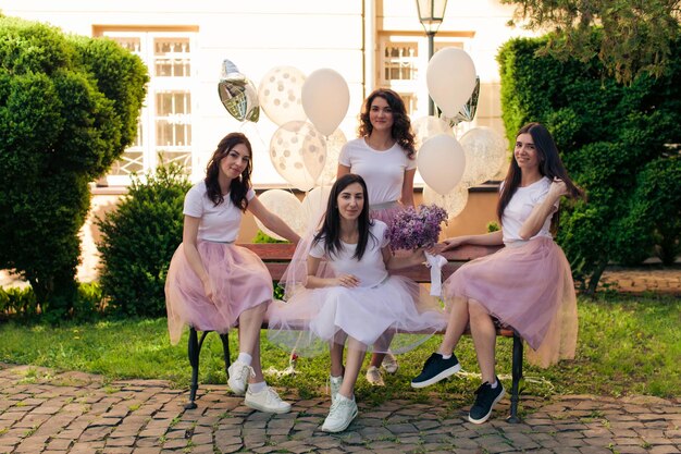 Hübsche Mädchen in flauschigen Röcken, die im Freien vor der Kamera posieren Freundinnen und Braut feiern Junggesellinnenabschied vor der Hochzeit