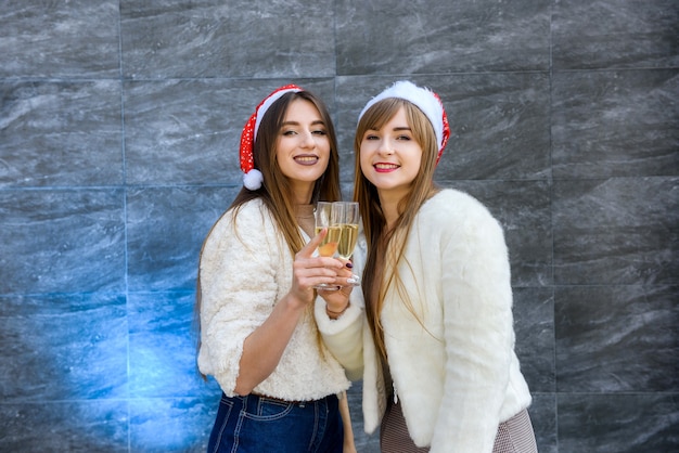 Hübsche Mädchen mit Champagnergläsern, die neues Jahr feiern. Zwei brünette Frauen in Pelzjacken