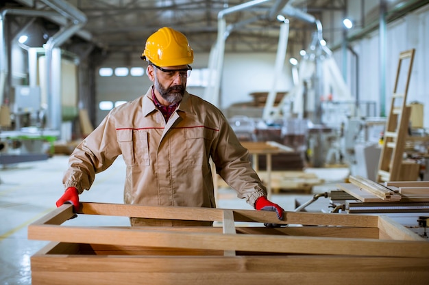 Hübsche mittlere gealterte Arbeitskraft, die in der Möbelfabrik arbeitet