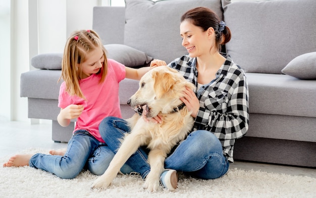 Hübsche Mutter und süße Tochter, die zu Hause mit einem entzückenden Hund spielt