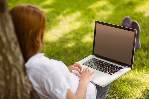 Hübsche Rothaarige, die mit ihrem Laptop sitzt