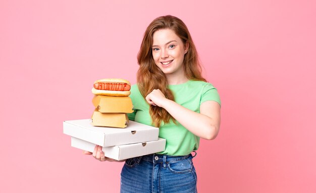 Hübsche rothaarige Frau, die Fast-Food-Boxen zum Mitnehmen hält