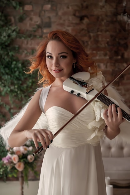 Hübsche, schlanke Frau mit Geige und Flügeln