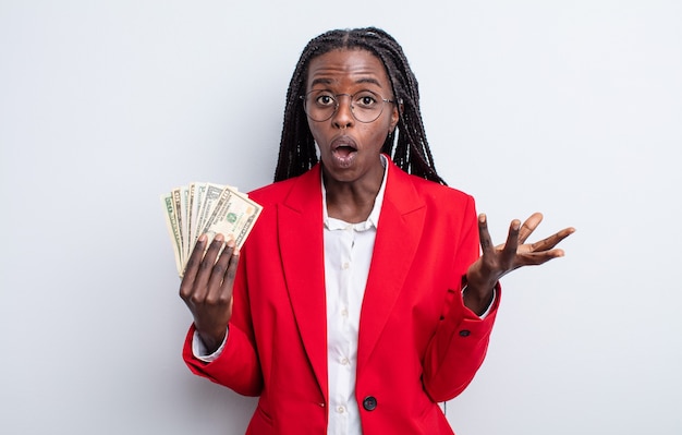 Hübsche schwarze Frau, die sich extrem schockiert und überrascht fühlt. Dollar-Banknoten-Konzept