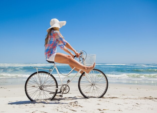 Hübsche sorglose Blondine auf einer Fahrradfahrt am Strand