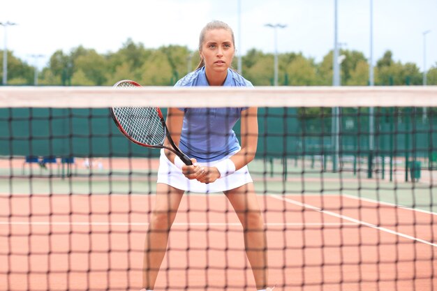 Hübsche Sportlerin mit Schläger am Tennisplatz. Gesunder Lebensstil.