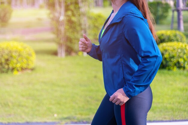 Hübsche sportliche Frau, die im Park im Sonnenaufganglicht joggt