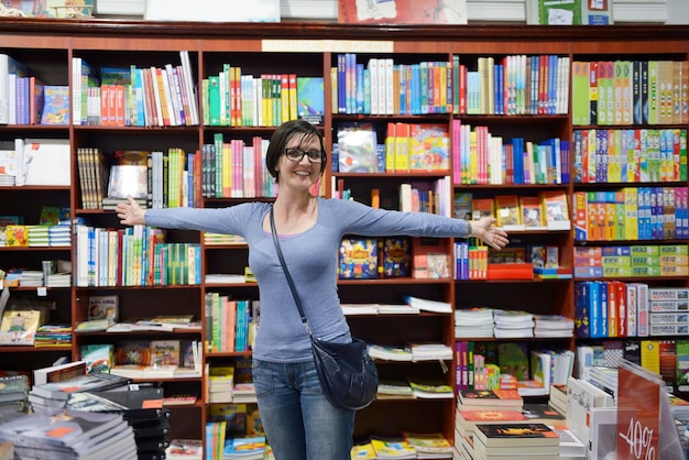 Hübsche Studentin, die am Bücherregal im Ladengeschäft der Universitätsbibliothek steht und nach einem Buch sucht