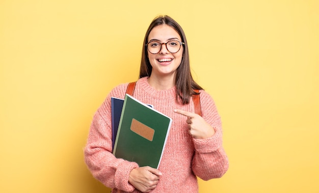 Hübsche Studentin, die aufgeregt und überrascht aussieht und auf die Seite zeigt