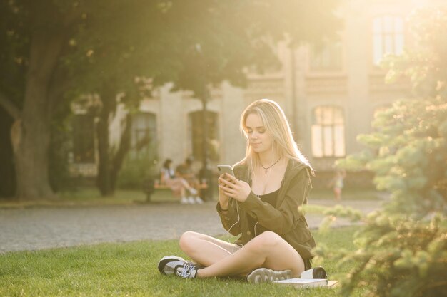 Hübsche Studentin nutzt Smartphone in der Pause auf Universitätshintergrund