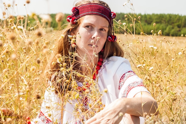 Hübsche ukrainische Frau kleidete in gestickter Kleidung auf dem Gebiet an