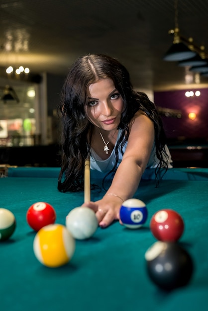 Hübsche und junge Frau, die Billard in der Kneipe spielt