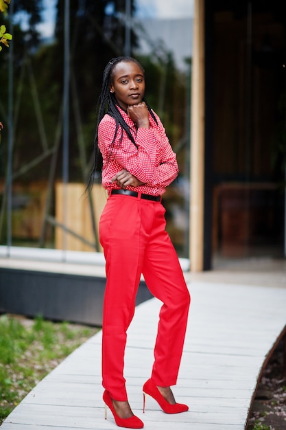 Hübsche Zöpfe Business Afroamerikaner Dame helle herrische Person freundlich tragen Büro rotes Hemd und Hose.