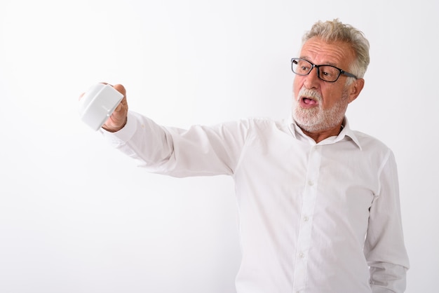 hübscher älterer bärtiger Mann, der leere Kaffeetasse verkehrt herum mit Brille auf Weiß hält