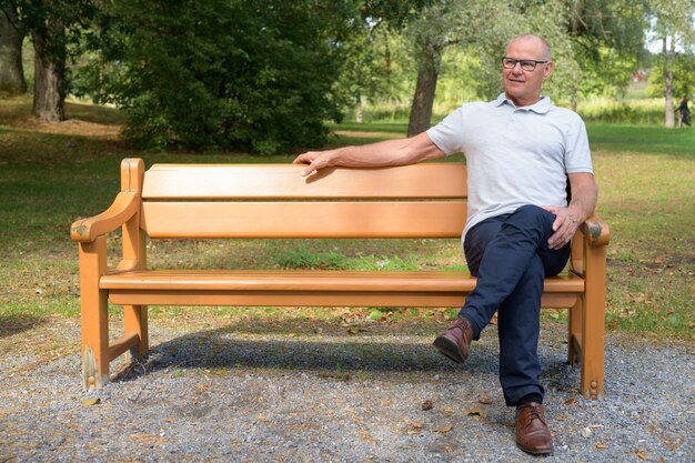 Hübscher älterer Mann, der am Park sitzt und sich entspannt