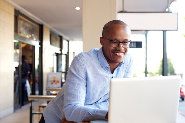 Hübscher afrikanischer Geschäftsmann, der mit Laptop arbeitet