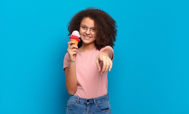 Hübscher Afro-Teenager, der mit einem zufriedenen, selbstbewussten, freundlichen Lächeln auf die Kamera zeigt und Sie auswählt. Sumer-Eis-Konzept