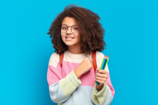 Hübscher Afro-Teenager, der sich glücklich, positiv und erfolgreich fühlt, motiviert, wenn er sich einer Herausforderung stellt oder gute Ergebnisse feiert