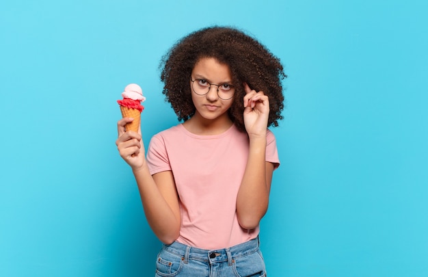 Hübscher afro-teenager, der sich verwirrt und verwirrt fühlt und zeigt, dass sie verrückt, verrückt oder verrückt sind