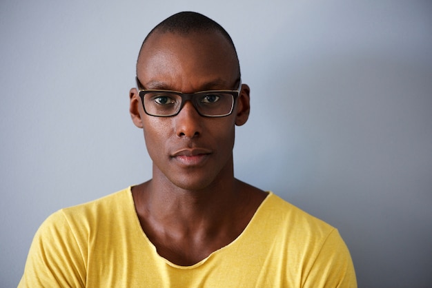 Hübscher Afroamerikanermann mit Gläsern gegen grauen Hintergrund