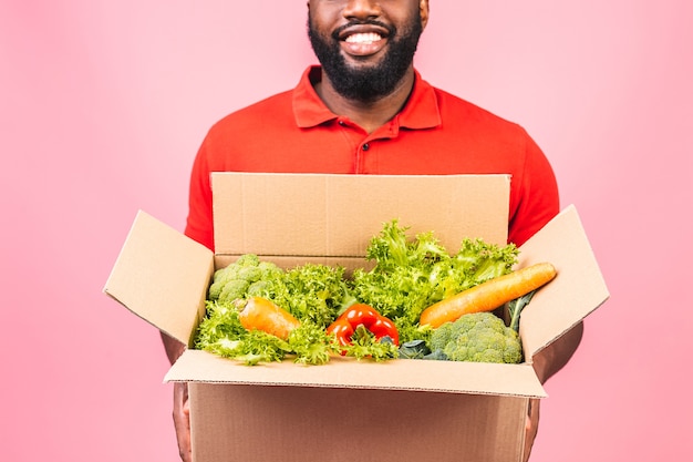 Hübscher afroamerikanischer lieferbote, der paketbox trägt