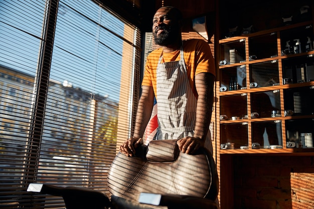 Hübscher afroamerikanischer Mann, der im Friseursalon am Fenster steht