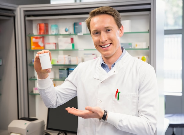 Hübscher Apotheker, der Medizinglas zeigt