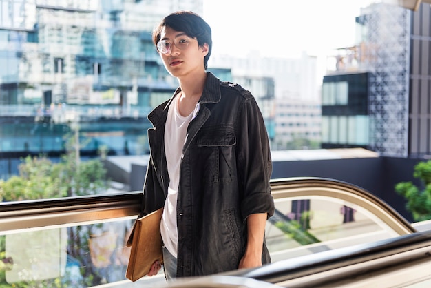 Hübscher asiatischer Kerl auf der Rolltreppe