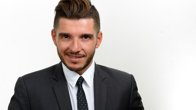 Hübscher bärtiger hispanischer geschäftsmann, der anzug auf weiß trägt