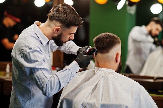 Hübscher bärtiger Mann am Friseursalon, Friseur bei der Arbeit.