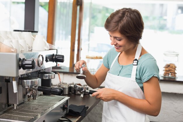 Hübscher Barista, der Kaffee drückt, mahlt