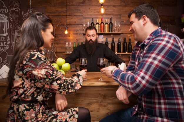 Hübscher Barkeeper im Gespräch mit Kunden am Tresen in einer Kneipe. Hipster-Kneipe.